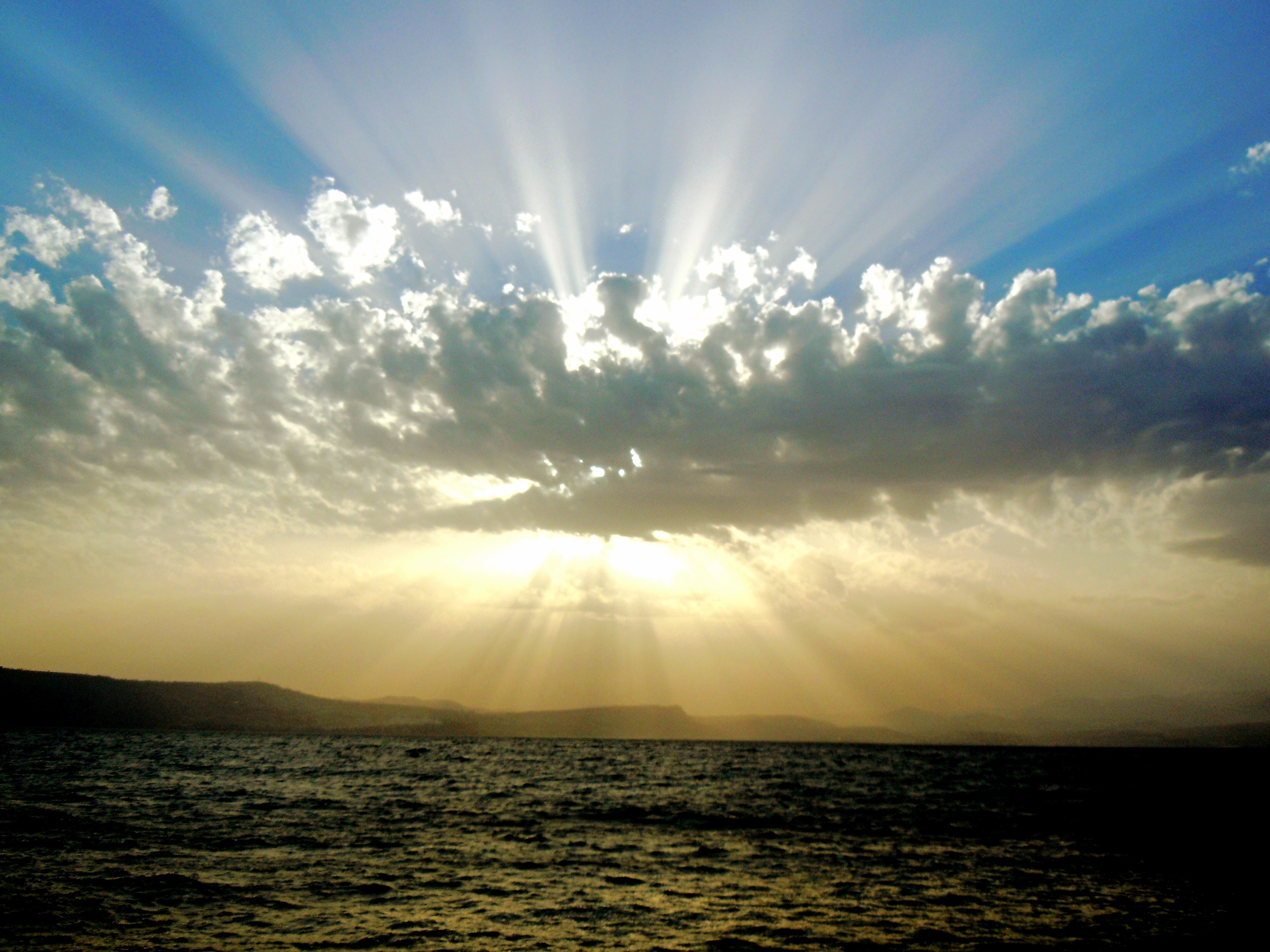 免费照片太阳躲在海洋上的一大片云后面