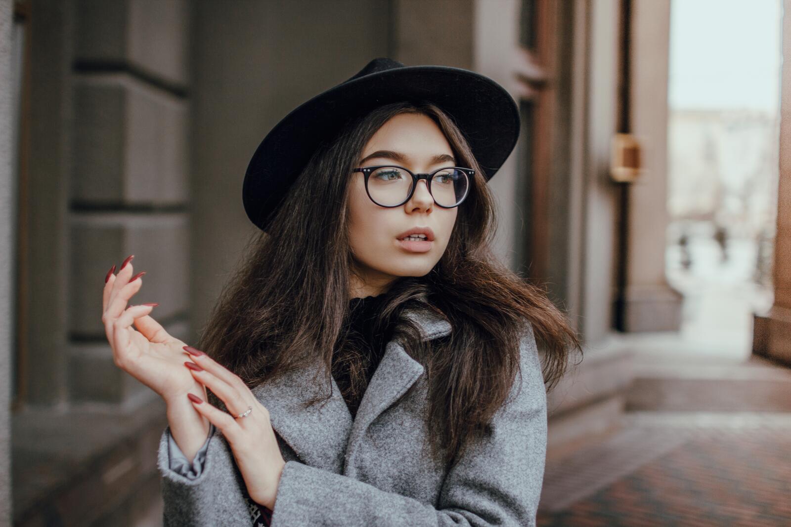 Free photo A brown-haired woman in a black hat and see-through glasses