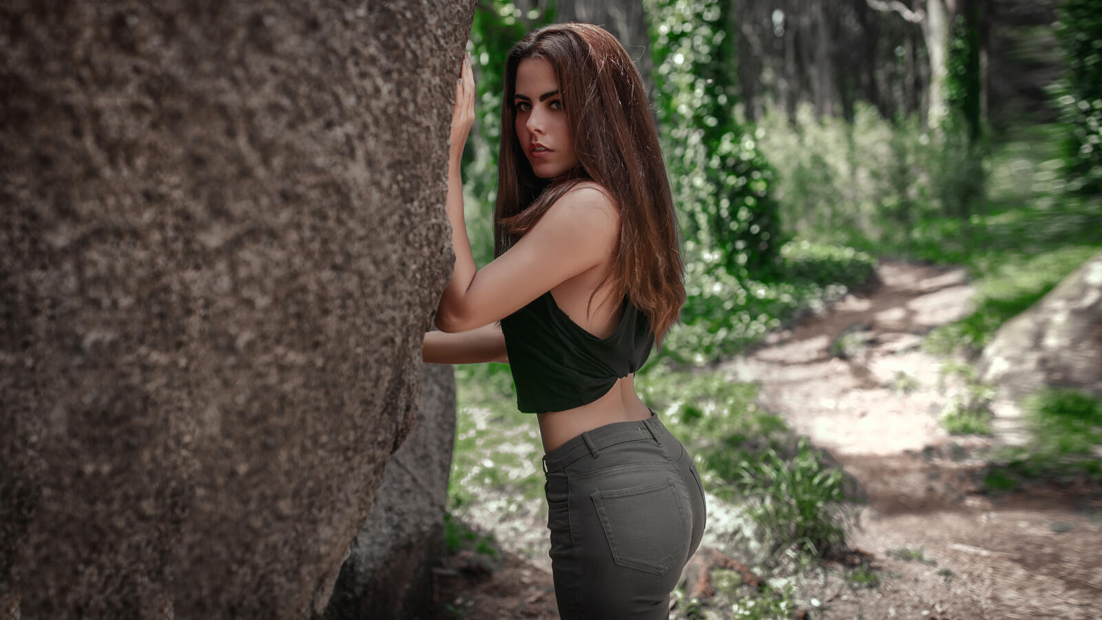 Free photo A brunette with a beautiful figure stands by a tree
