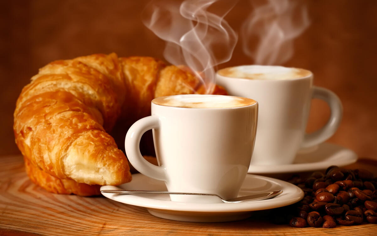 Two cups of coffee and a croissant
