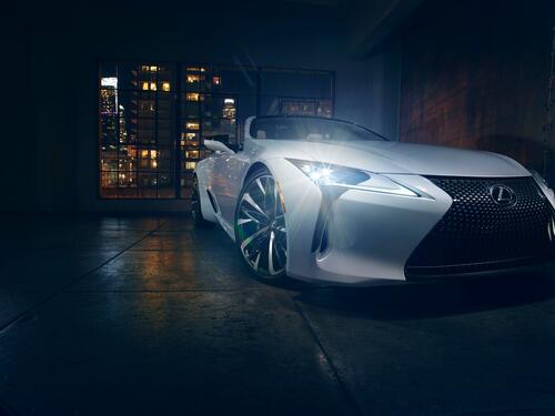 White Lexus LC convertible with headlights on.