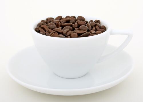 A white cup filled with coffee beans.