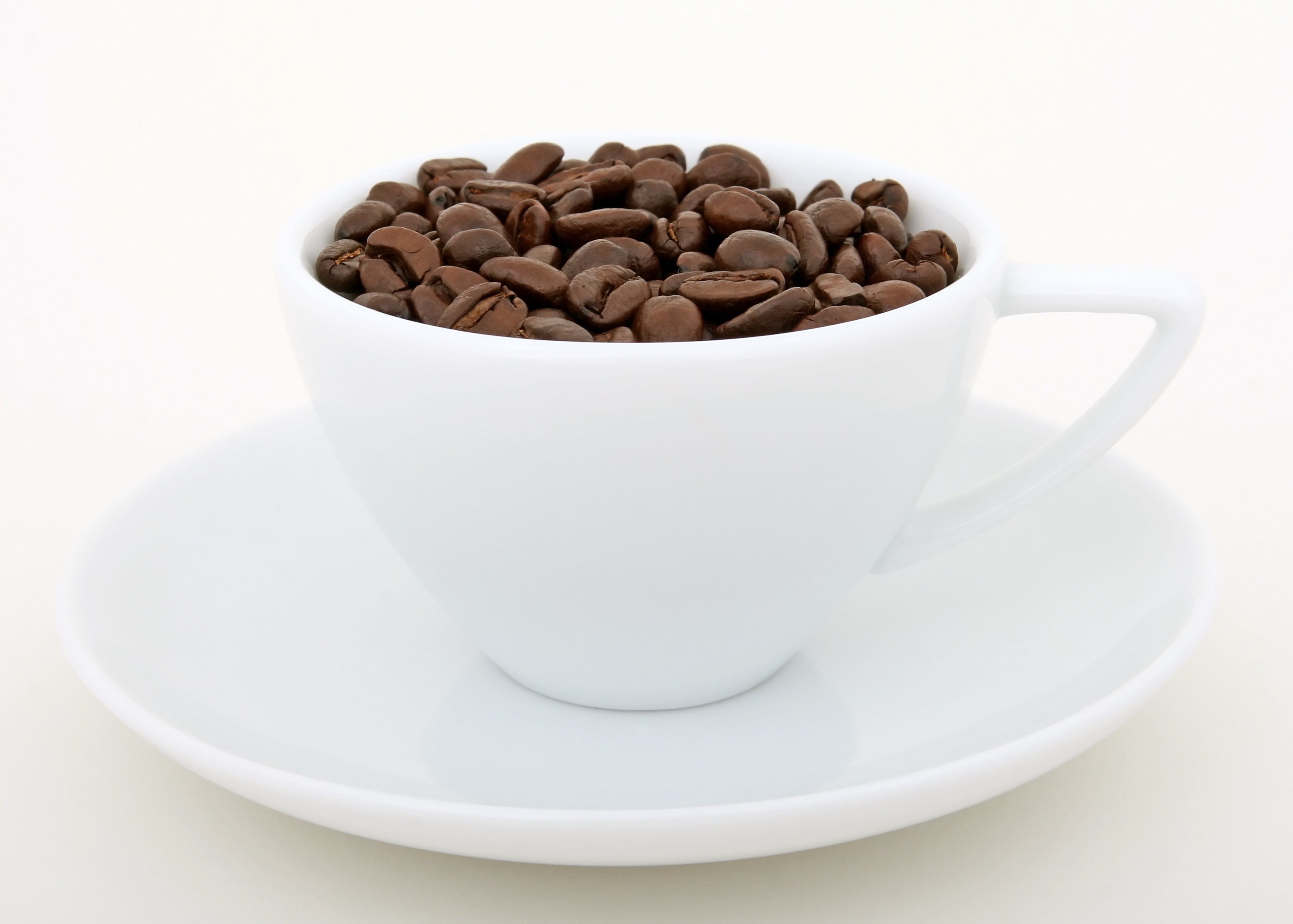 Бесплатное фото Белая чашка наполненная зернами  кофе