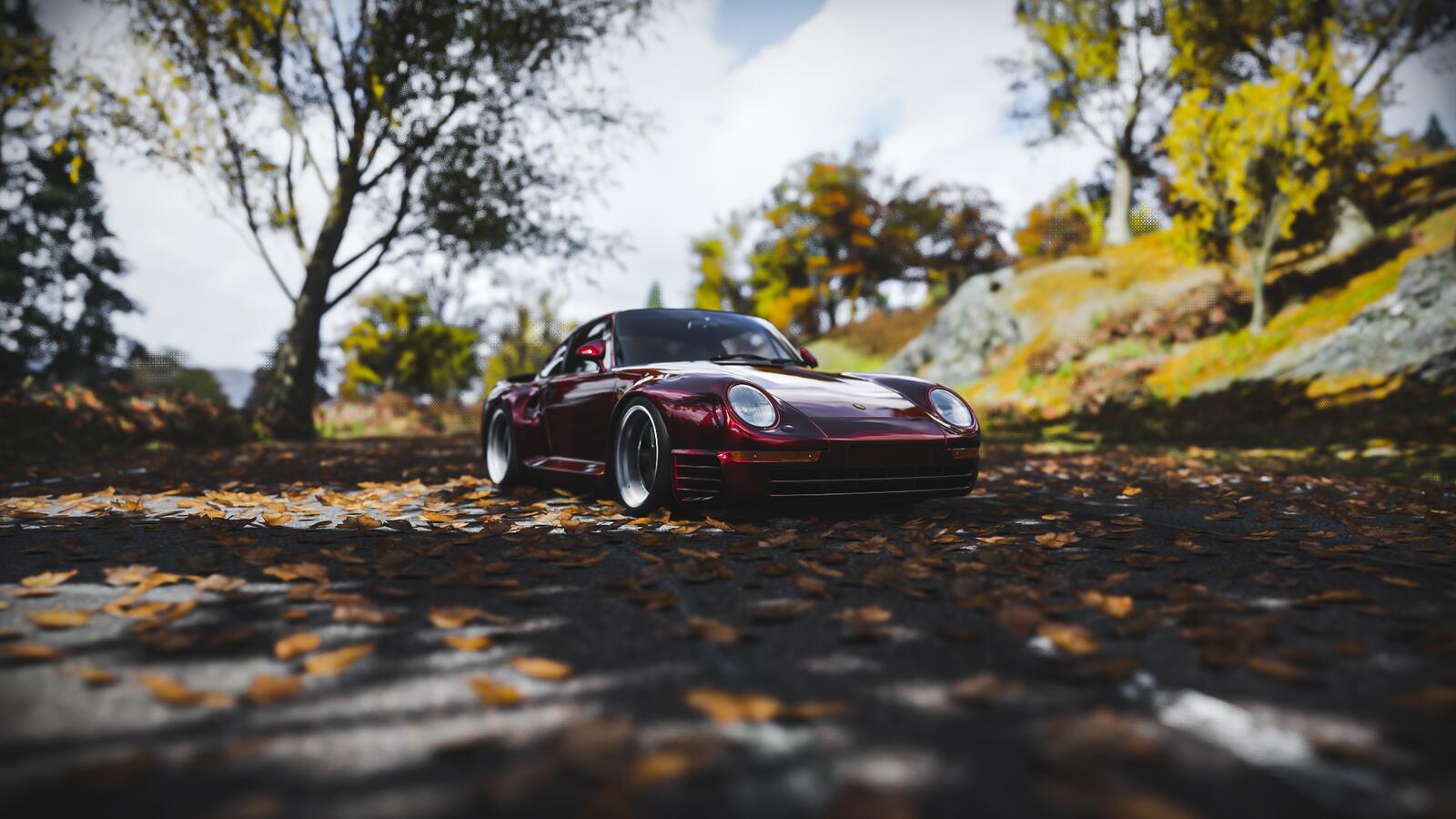 Free photo Red porsche 959 stands on the road with fallen leaves