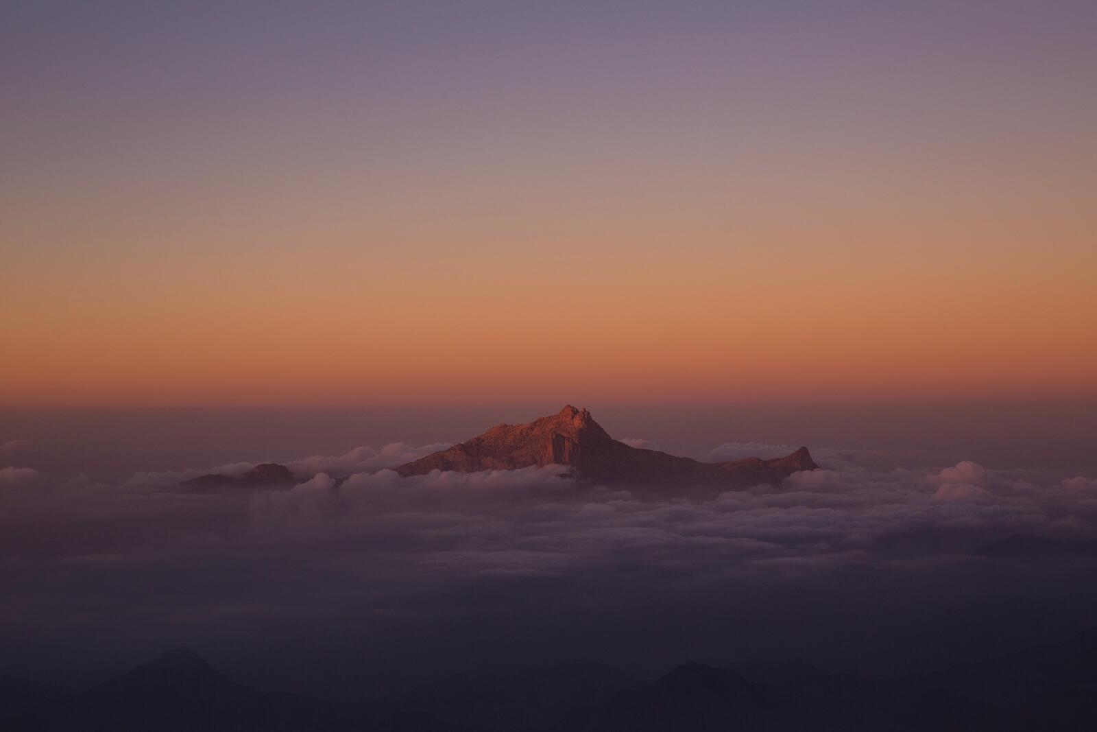 Бесплатное фото Вершина горы виднеются через густые облака