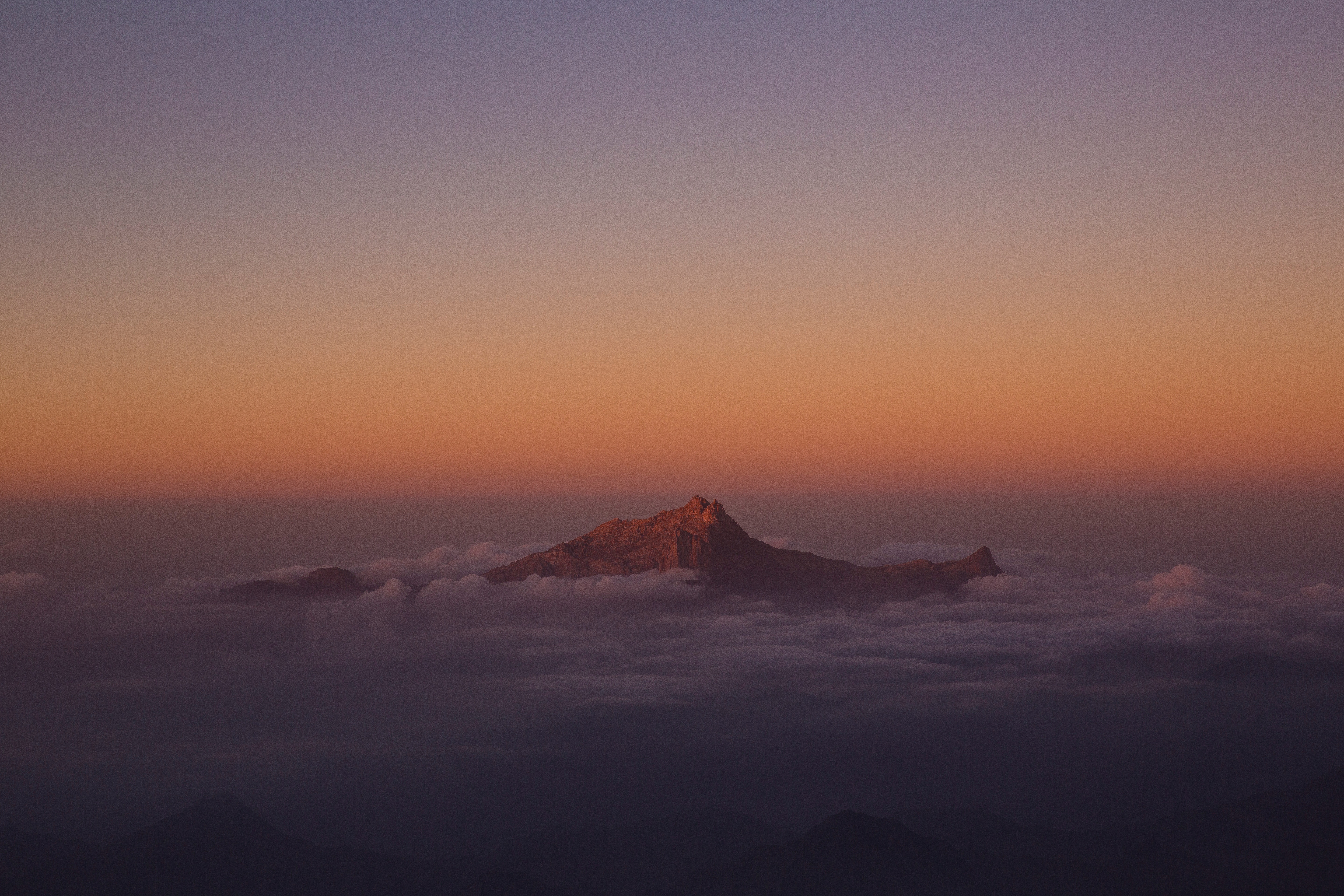 Бесплатное фото Вершина горы виднеются через густые облака