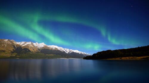 Green northern lights over the lake in the evening time