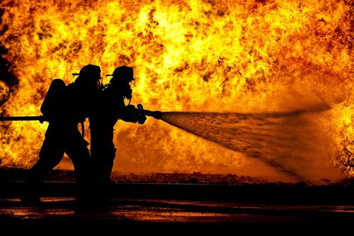 Силуэт пожарников на фоне большого пожара