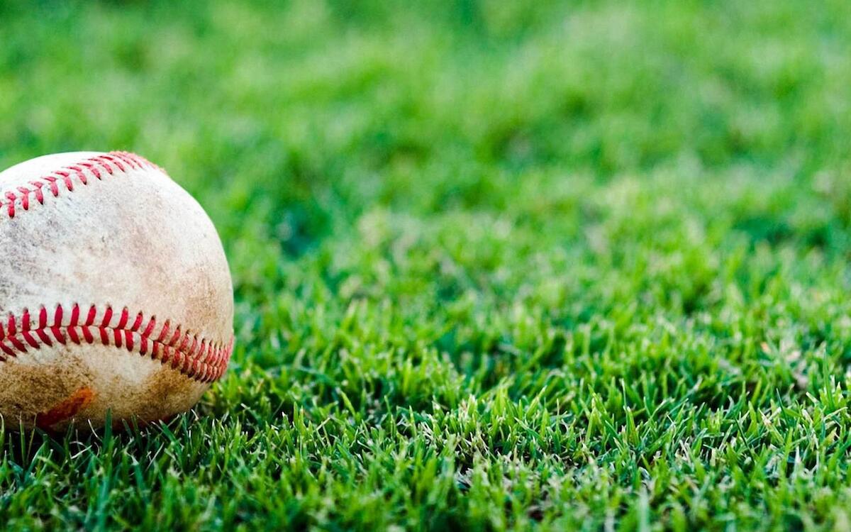 Мячик для бейсбола лежит на зеленой траве