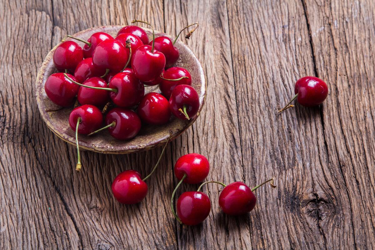 Ripe cherries on a plate on a wooden background